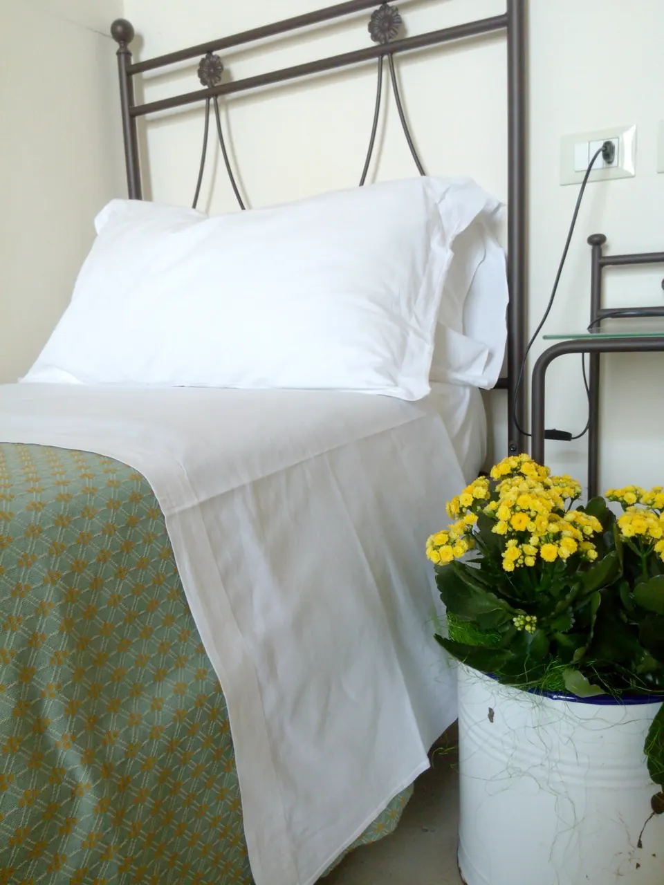 Letto con lenzuola bianche e fiori gialli